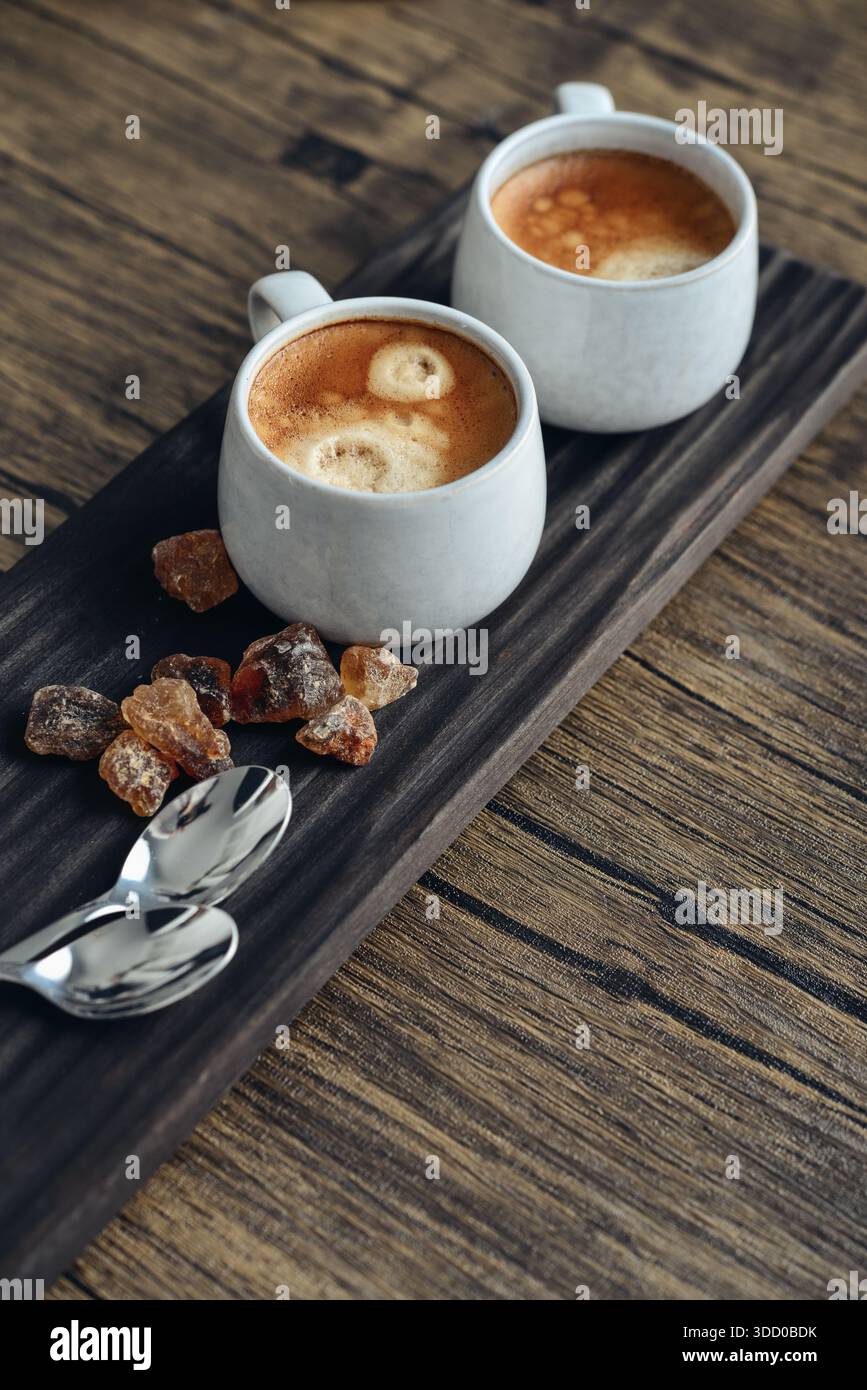 Due tazze di caffè su vassoio di legno con primo piano di zucchero di canna Foto Stock
