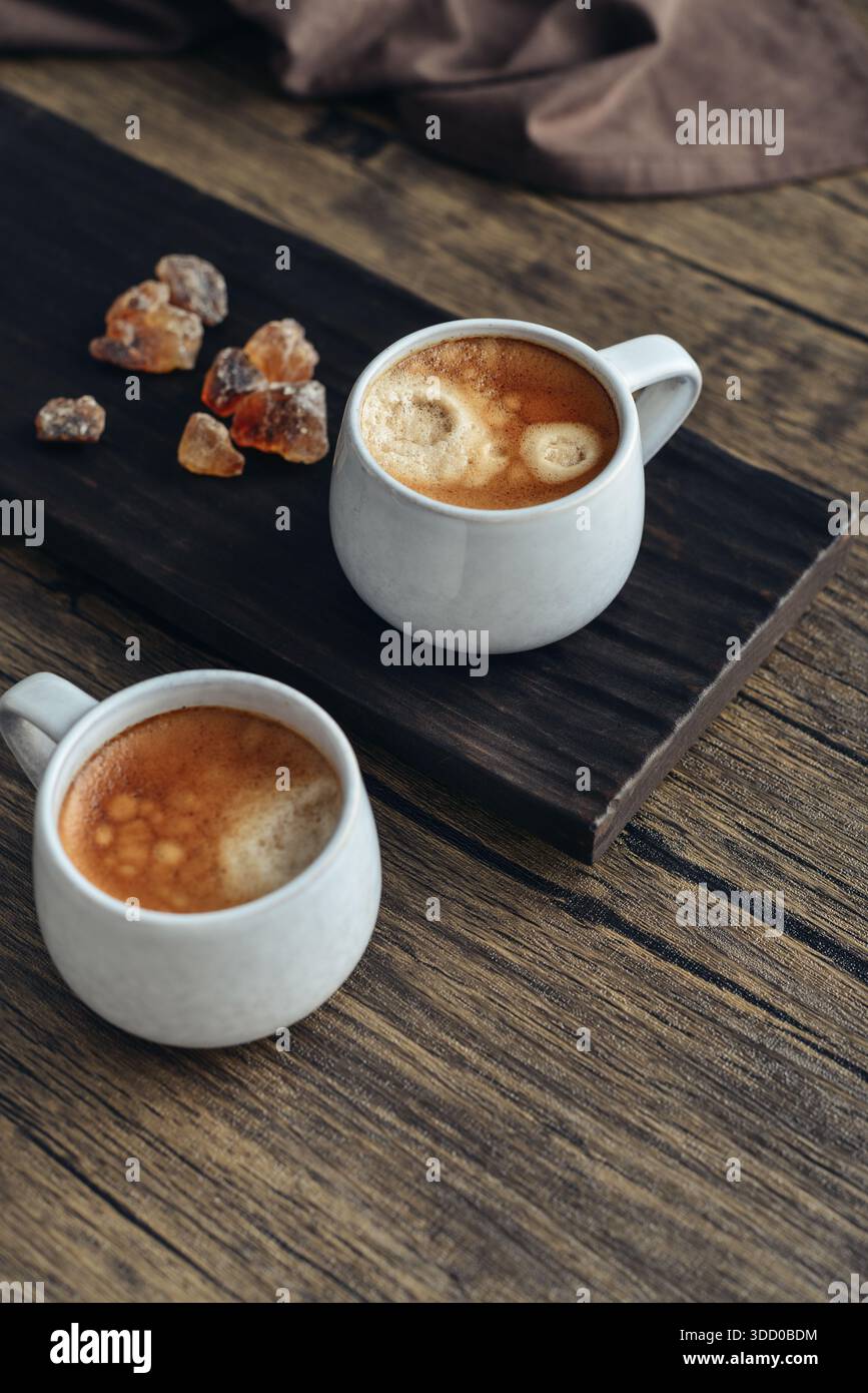 Due tazze di caffè su vassoio di legno con primo piano di zucchero di canna Foto Stock