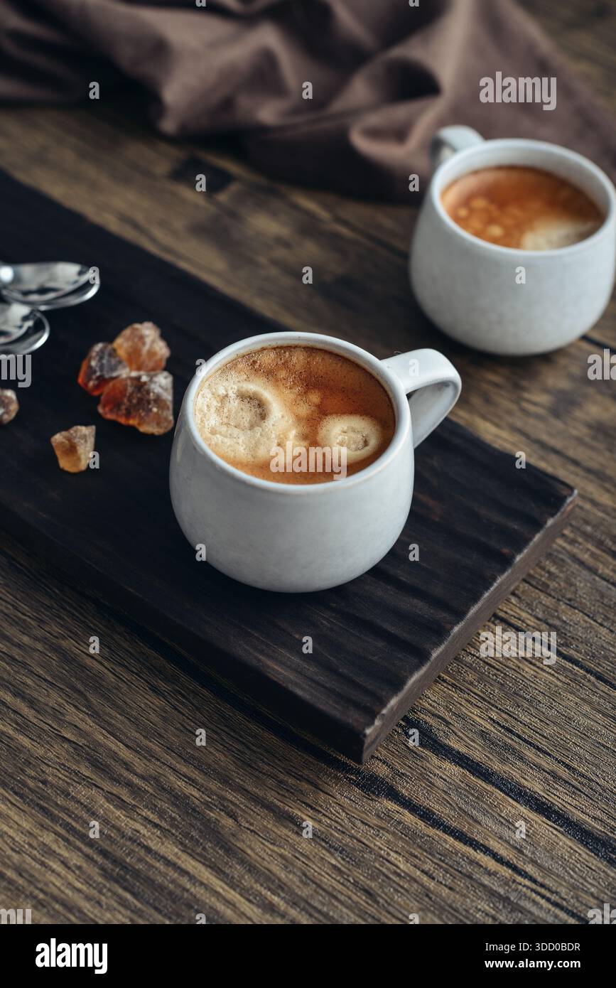 Due tazze di caffè su vassoio di legno con primo piano di zucchero di canna Foto Stock