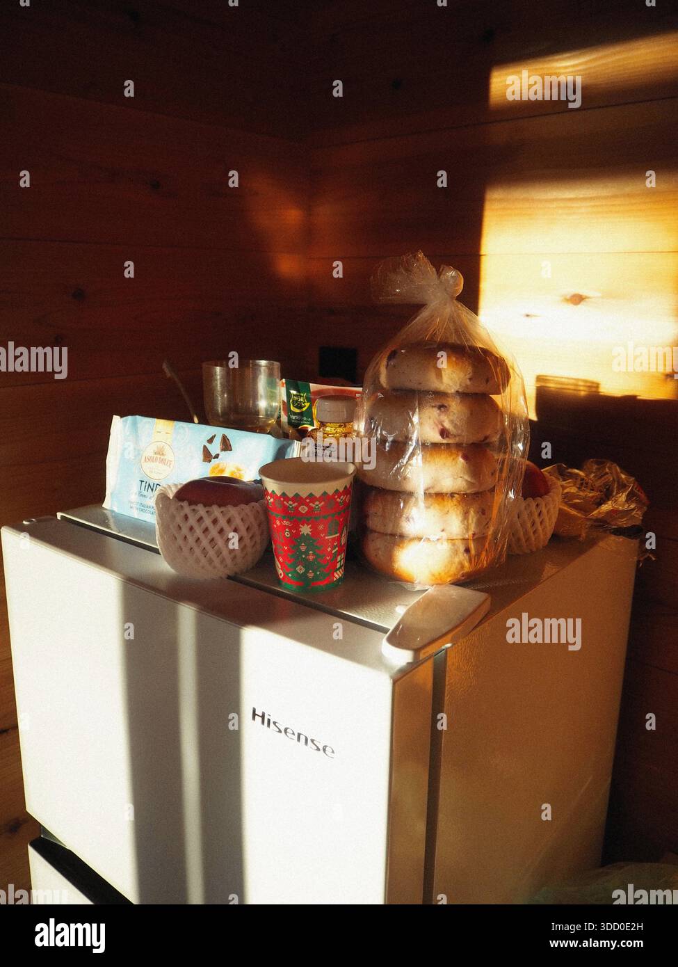 Cucina mattutina con prodotti per la colazione su un piccolo frigorifero illuminato dalla luce calda del sole in un intimo interno in legno Foto Stock