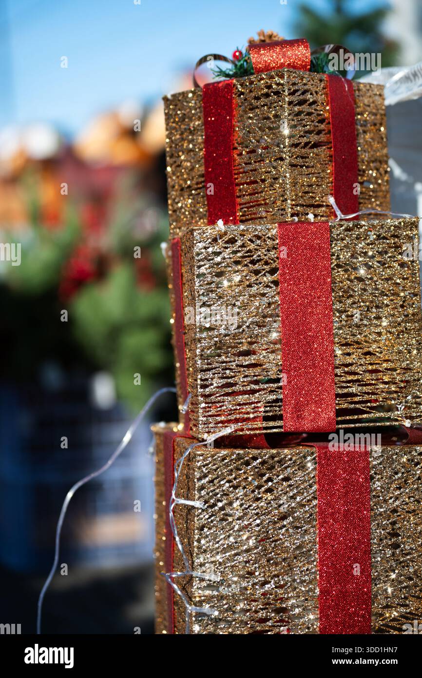 Pila di tre scatole regalo dorate con nastri rossi . Regali per Natale e Capodanno Foto Stock
