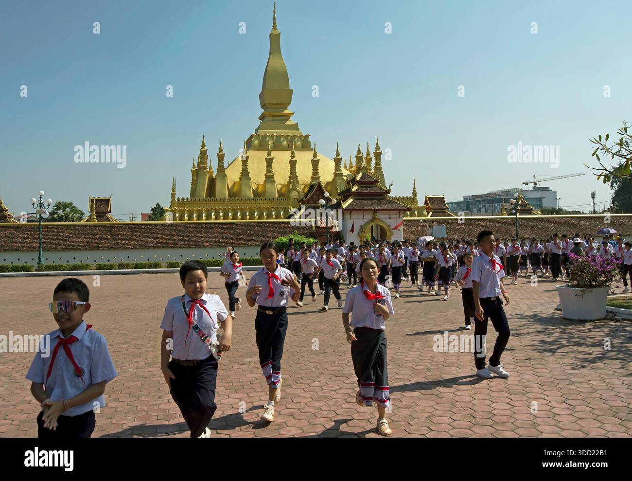 gli scolari loatisti corrono con gioia dopo essere stati allontanati dalla classe fuori dal tempio di pha che luang, vientiane, laos Foto Stock
