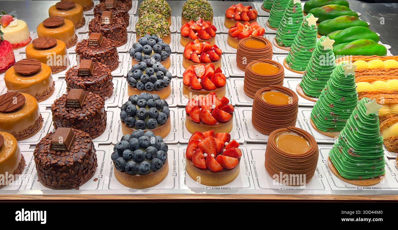 Vivace assortimento di mini crostate, torte e dessert di pasticceria che riempiono una vetrina Foto Stock