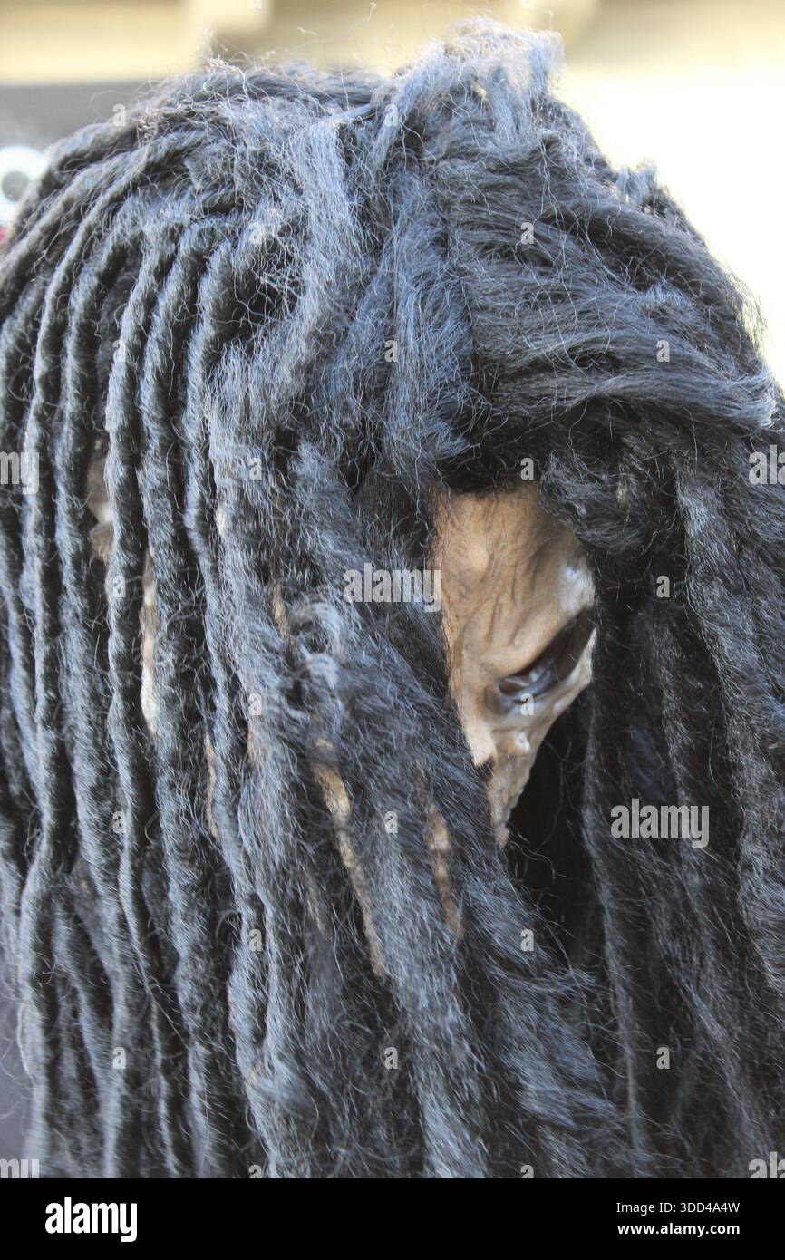 Costume di scheletro con maschera dreadlock indossata da persona in abito scuro, che rappresenta la morte Foto Stock