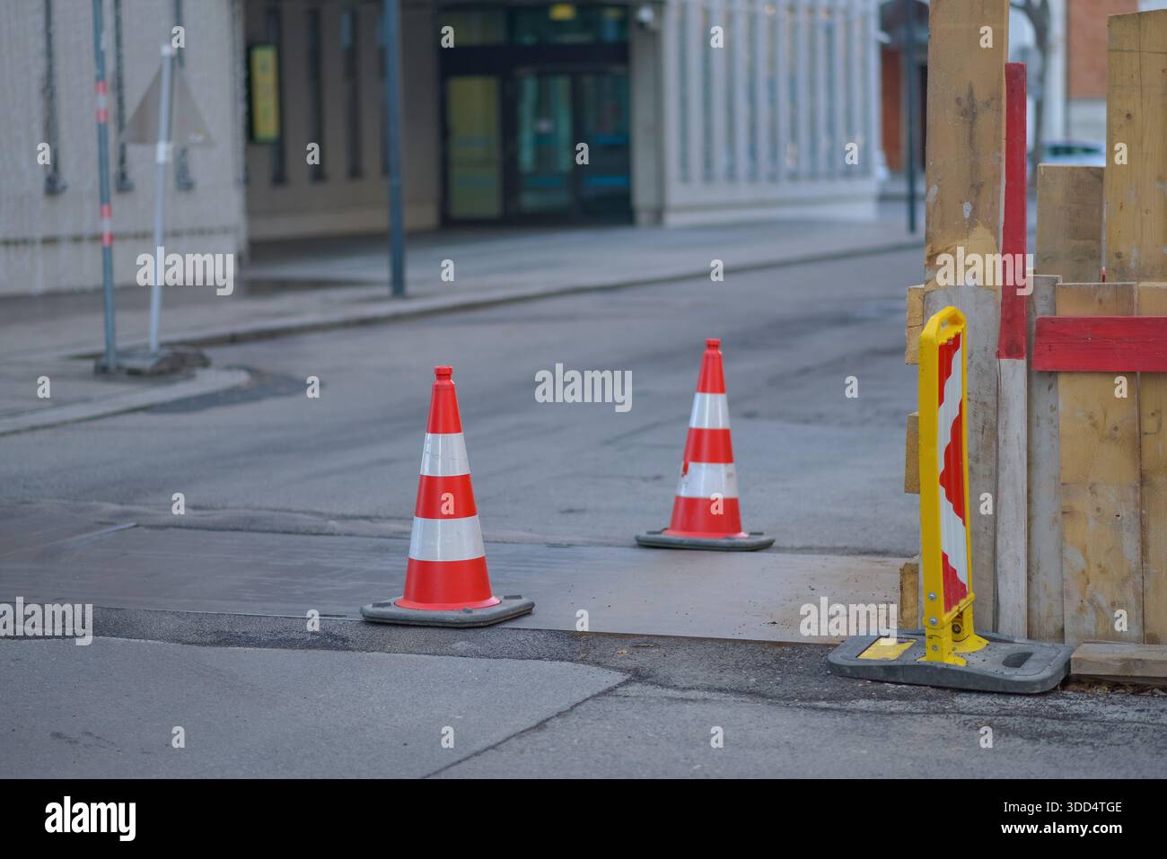 Coni stradali e barriere di sicurezza che segnalano la zona di costruzione stradale su una strada cittadina. Infrastrutture urbane, lavori di riparazione, sicurezza dei trasporti, avvertenza c Foto Stock