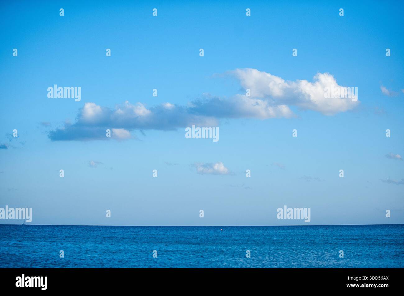 Mare e cielo blu con nuvole bianche sparse su un orizzonte oceanico calmo, paesaggio marino tranquillo estivo Foto Stock