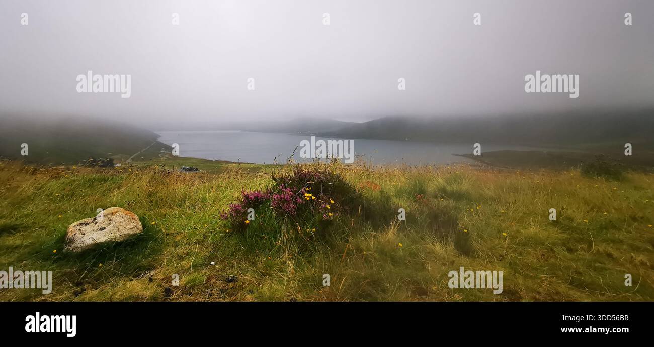 Un tranquillo lago avvolto da nebbia alla deriva in una fredda mattina autunnale nelle Highlands scozzesi, dove l'acqua calma e le nuvole basse creano una scena tranquilla e suggestiva Foto Stock