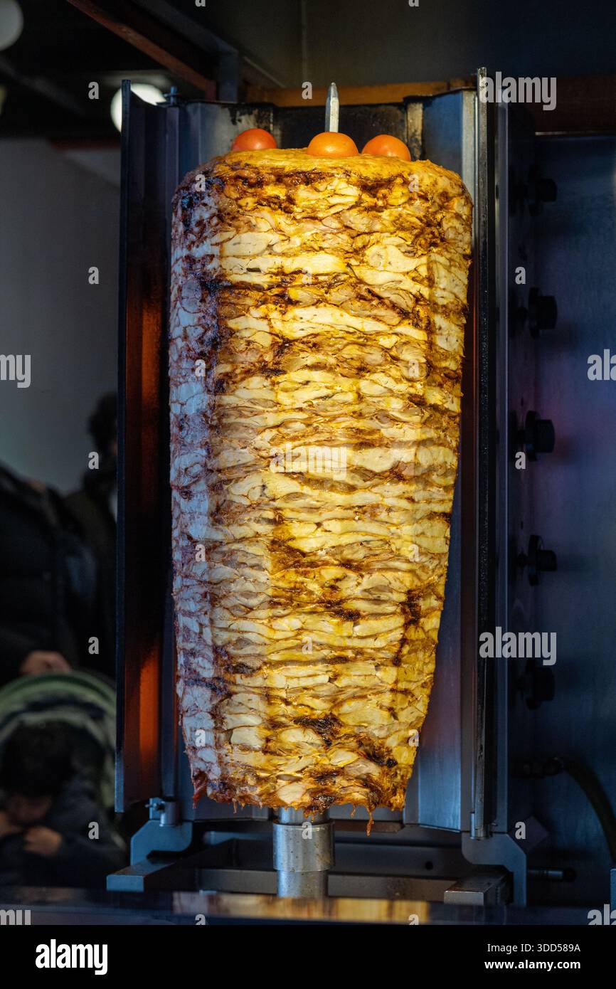 Primo piano di uno chef che affetta la tradizionale carne di kebab di donatore turco da una girarrosto verticale Foto Stock