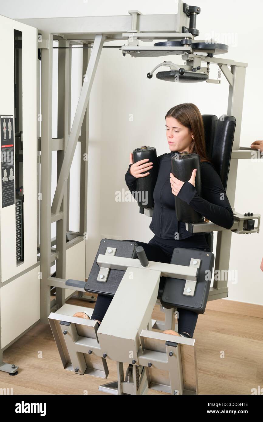 Giovane donna che esegue un allenamento di base con attrezzature da palestra specializzate. Concentrandosi sullo sviluppo del fitness e sull'allenamento di forza Foto Stock