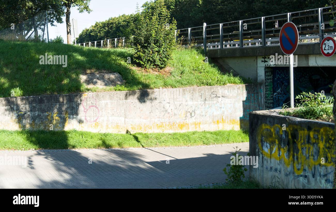 Sottopassaggio in cemento con graffiti colorati e vari segnali stradali che creano un'atmosfera urbana e industriale. Foto Stock