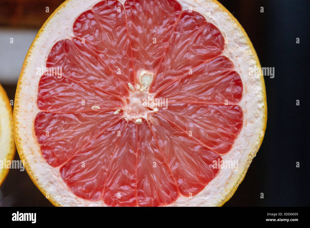 Primo piano di un pompelmo rosa succoso a metà che mostra una ricca consistenza di polpa di agrumi Foto Stock