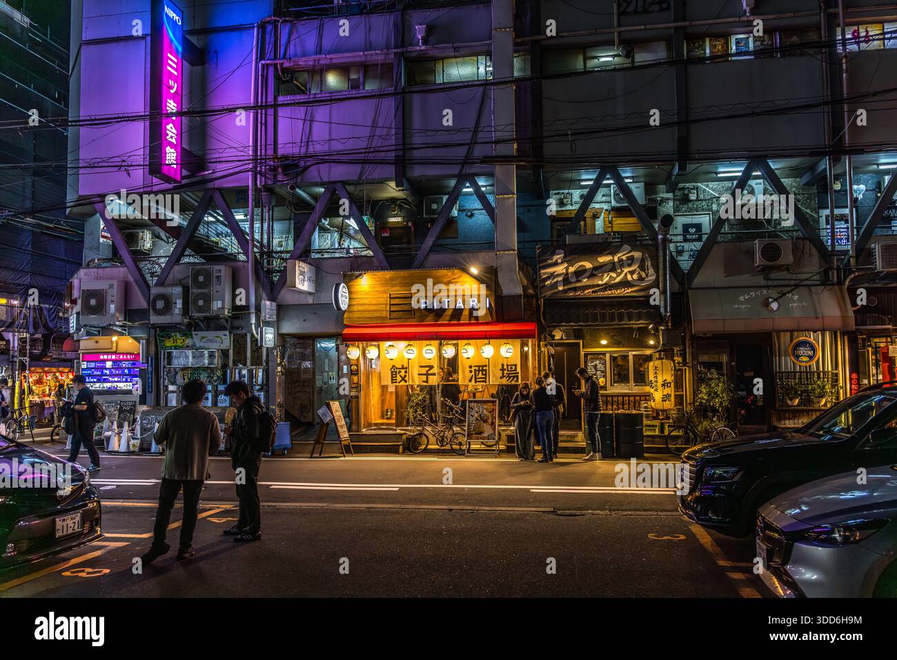 Persone in piedi di fronte al ristorante Pitari con luci al neon a Osaka, prefettura di Osaka, Giappone Foto Stock