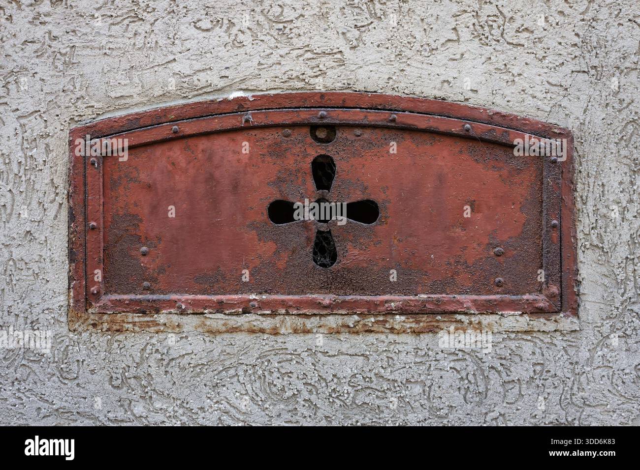 Porta della cantina di carbone in ferro d'epoca con bocca a quadrifoglio ornata a Colonia Ehrenfeld, architettura del XIX secolo. Consistenza ruvida su pareti in gesso grigio ruvido Foto Stock