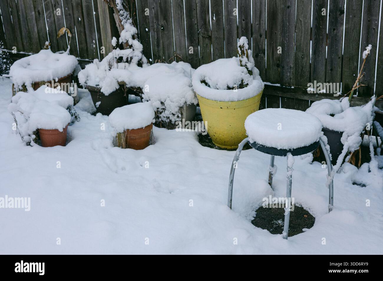Coperte di neve diverse pentole e uno sgabello in un cortile. E' una fredda giornata invernale con un ambiente bianco. Foto Stock