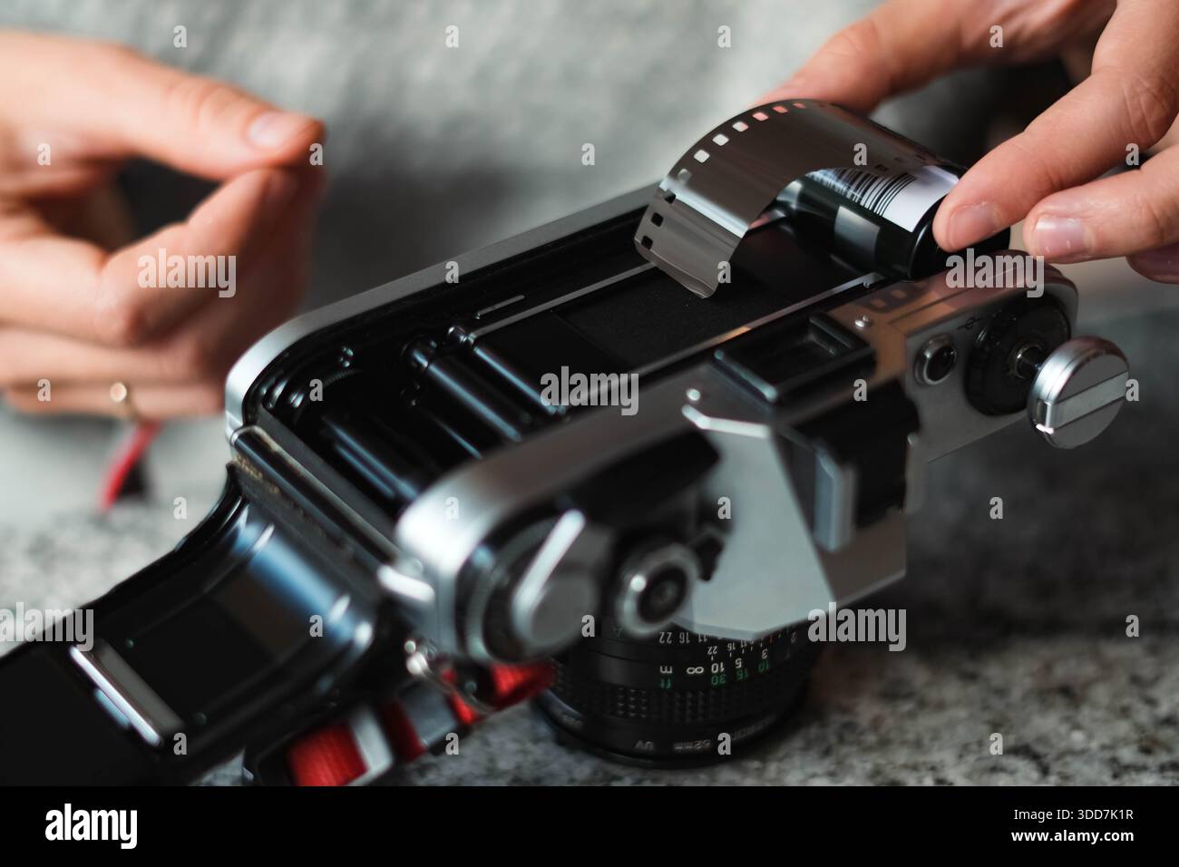 Le mani di una ragazza preparano una telecamera analogica. Le dita di un fotografo esperto inseriscono la pellicola all'interno della fotocamera. Stile vintage, cultura hipster. Foto Stock
