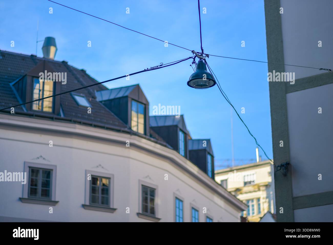 Lampioni sospesi da cavi tra i classici edifici europei sotto un cielo azzurro. Foto Stock