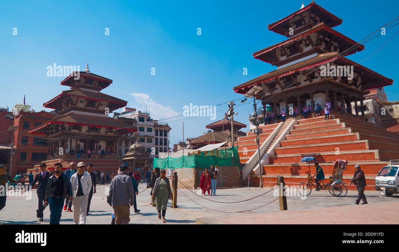 Due templi in stile nepalese su una piazza affollata con gente che cammina, mostrando una vivace vita urbana e un'architettura storica. Foto Stock
