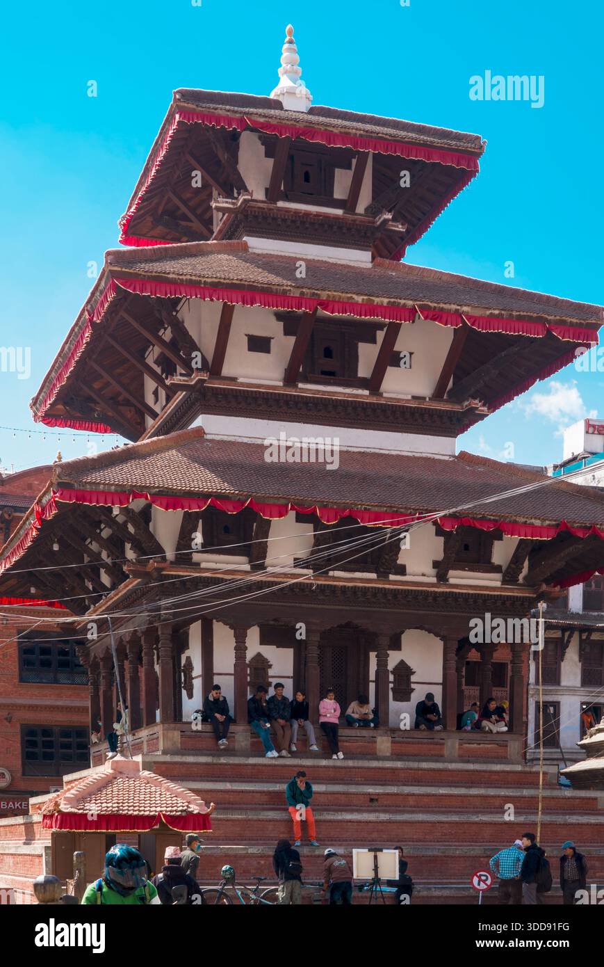 Tempio tradizionale a più livelli con persone in piedi e a piedi sui gradini di pietra, che riflettono l'architettura storica e la vita religiosa quotidiana in un Foto Stock