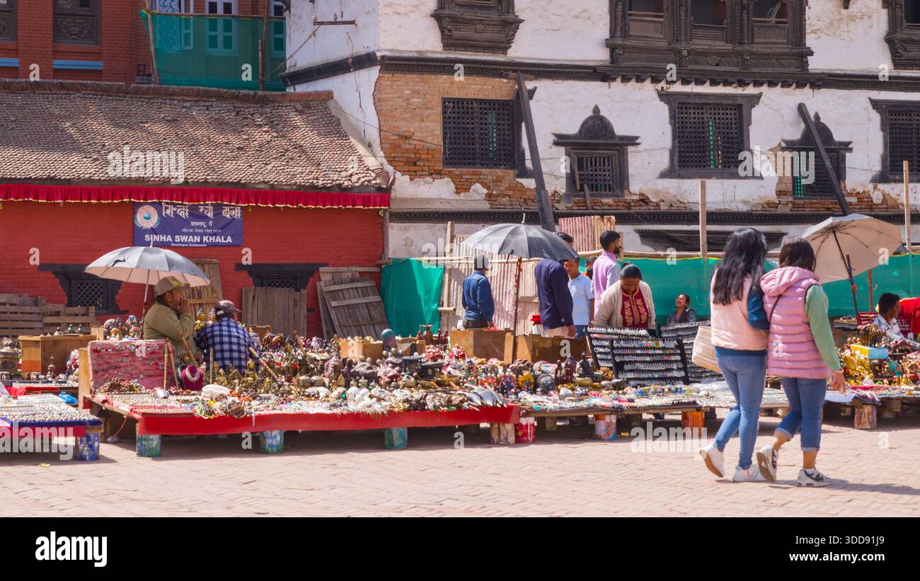 Le persone passeggiano attraverso un mercato con bancarelle piene di prodotti locali, che mostrano il vivace commercio e la tradizione culturale. Foto Stock