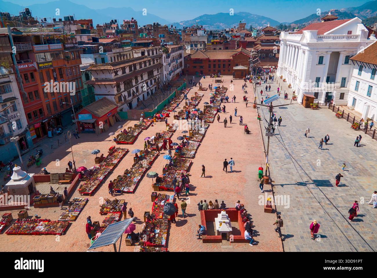 Vista aerea di una vivace piazza del mercato circondata da montagne ed edifici storici. Foto Stock