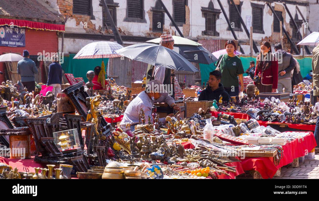 Colorato mercato dell'artigianato con visitatori e venditori sotto ombrelli luminosi. Foto Stock