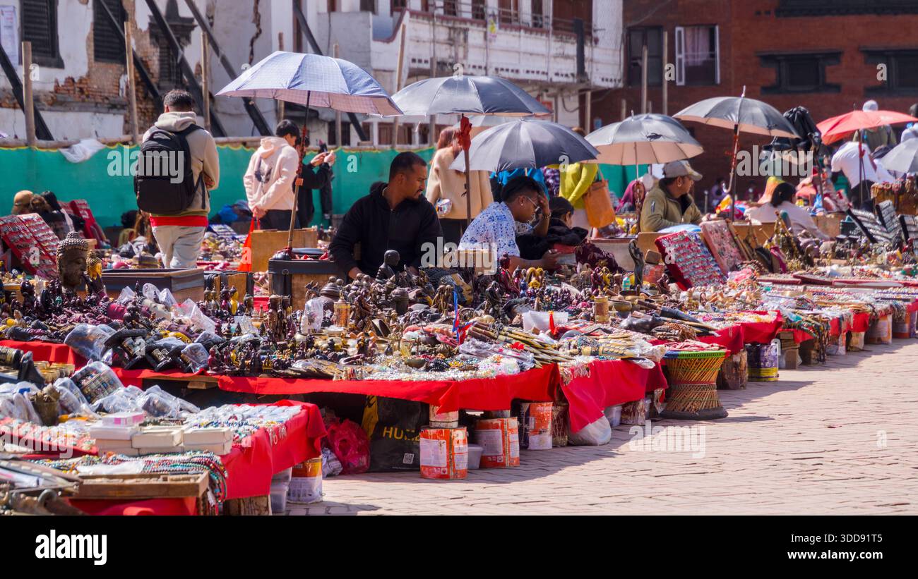 Colorato mercato dell'artigianato con visitatori e venditori sotto ombrelli luminosi. Foto Stock