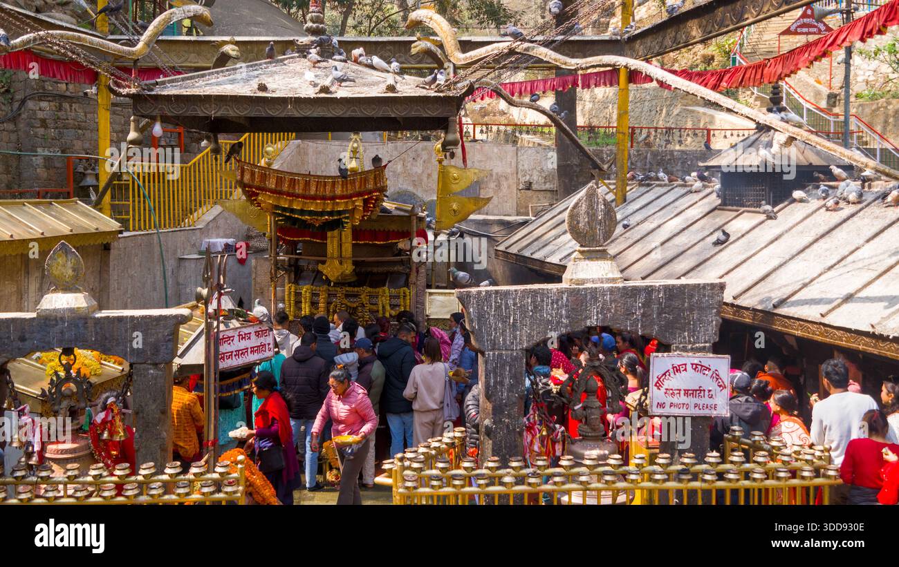 Le persone si riuniscono di fronte a un tempio riccamente decorato per una cerimonia religiosa, creando una vibrante scena spirituale. Foto Stock