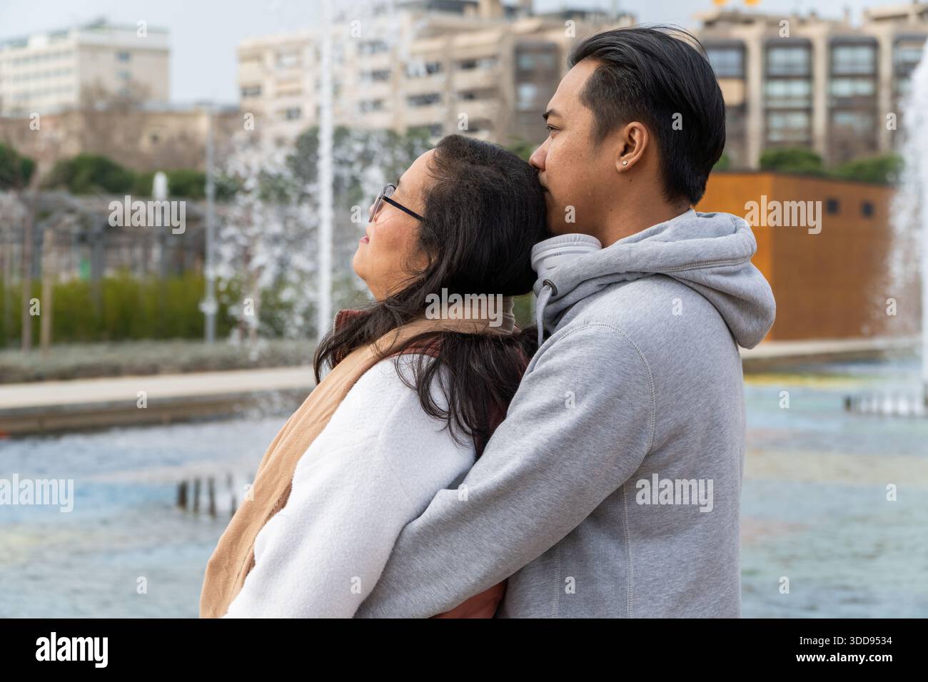 Felice uomo e donna asiatici che abbracciano il parco mentre guardano l'orizzonte con speranza Foto Stock