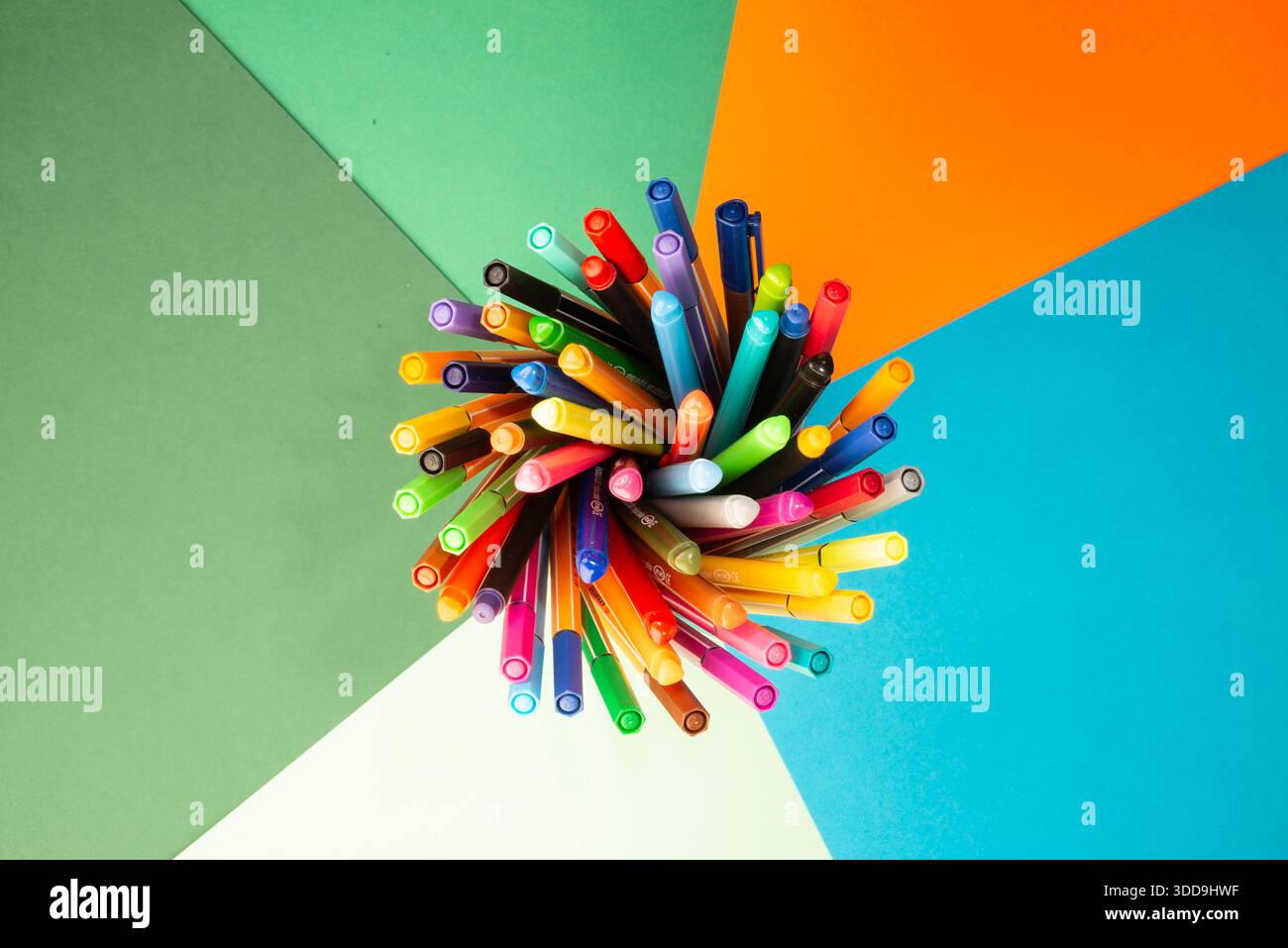 Concetto di spazio di lavoro creativo con penne multicolore disposte in un motivo radiale, che rappresenta innovazione, lavoro di squadra e pensiero strategico Foto Stock