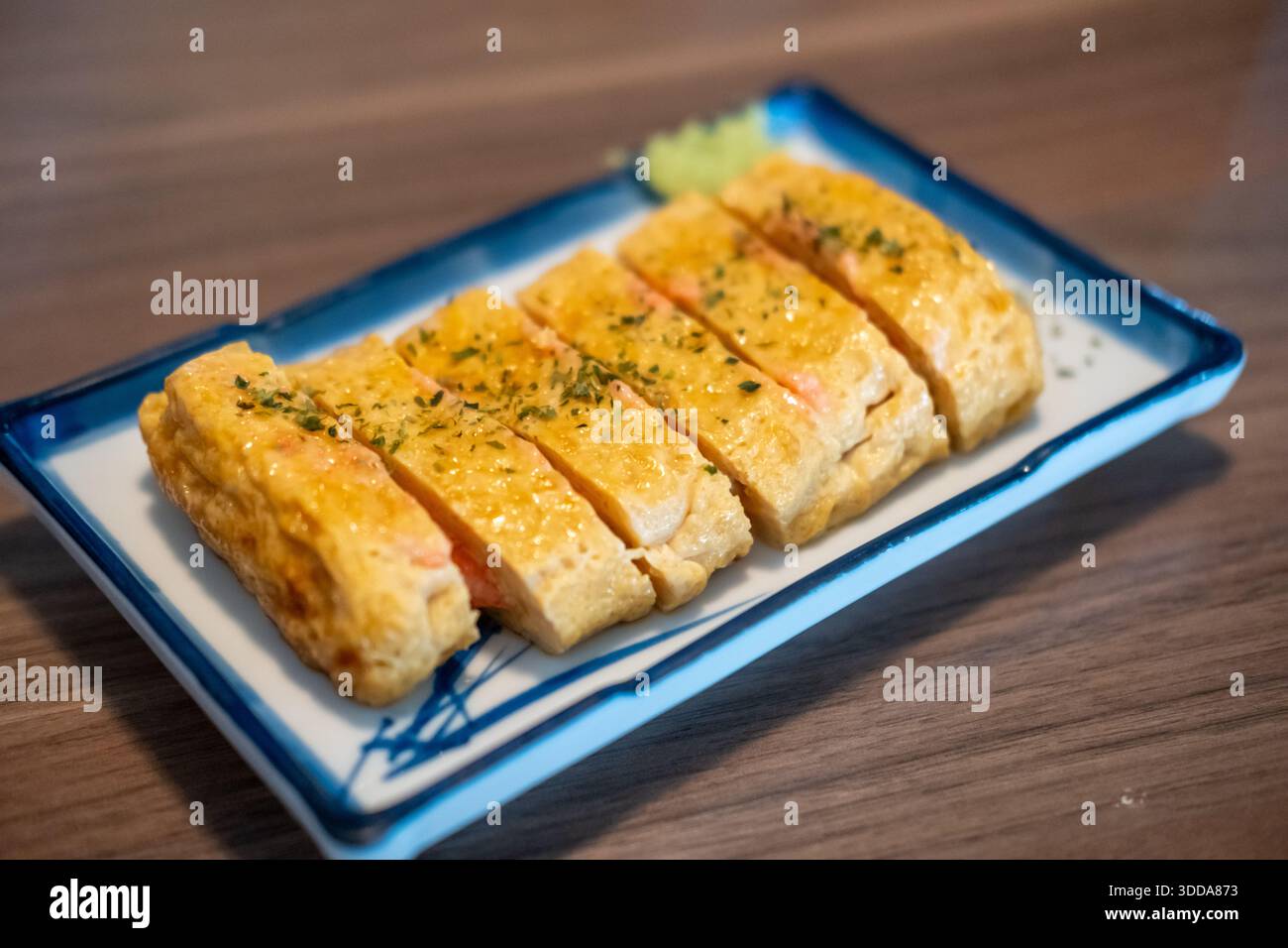 Tamagoyaki, un'omelette giapponese preparata arrotolando diversi strati di uova sbattute fritte, servita su un piatto. Foto Stock
