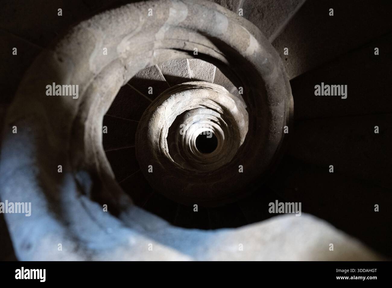 Una scala a chiocciola vista dall'alto, che mostra intricati lavori in pietra e ombre Foto Stock