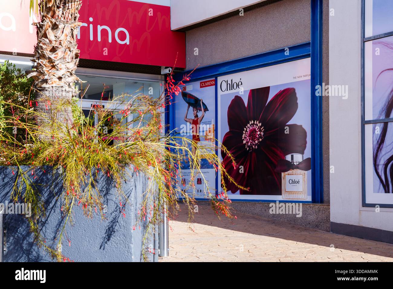 Un primo piano di un annuncio di profumo Chloé con un fiore scuro e una bottiglia di fragranza, situato vicino all'ingresso del centro commerciale la Marina con i g Foto Stock