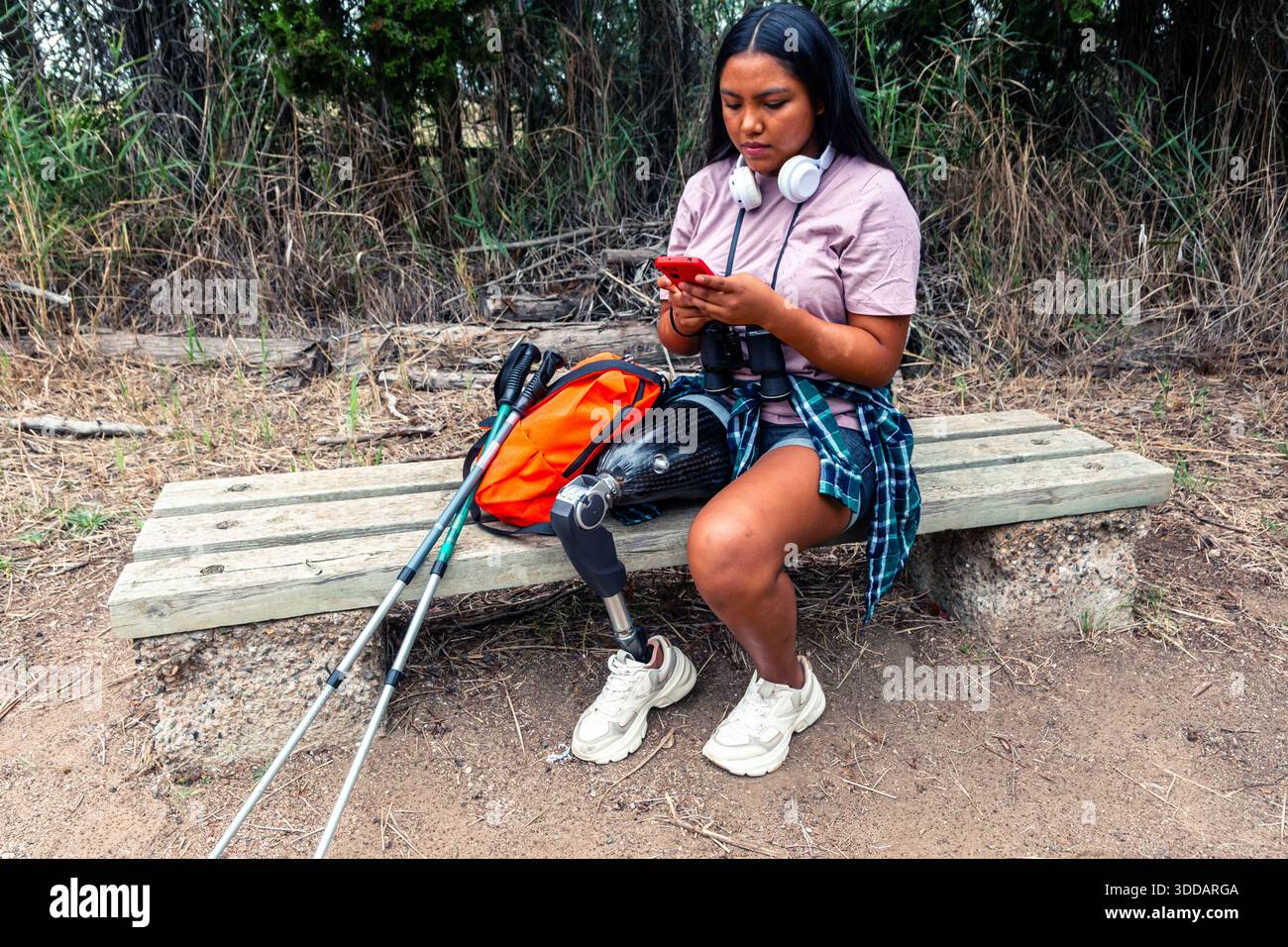 Giovane donna che fa trekking, osserva la natura e si connette digitalmente Foto Stock