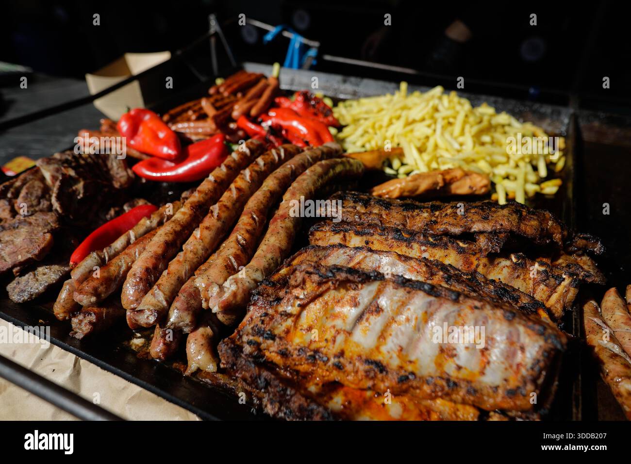 Prodotti a base di carne (mici, costolette di maiale, salsicce, patatine fritte) su una griglia esterna in metallo carbone. Foto Stock