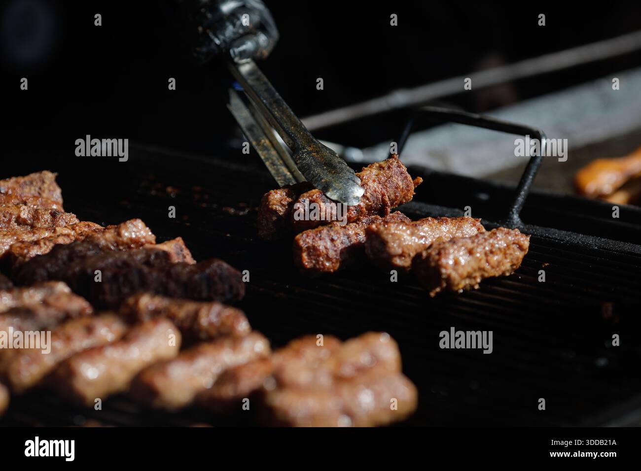 mici tradizionali rumeni (mititei o carne macinata laminata) su una griglia esterna in metallo carbone. Foto Stock