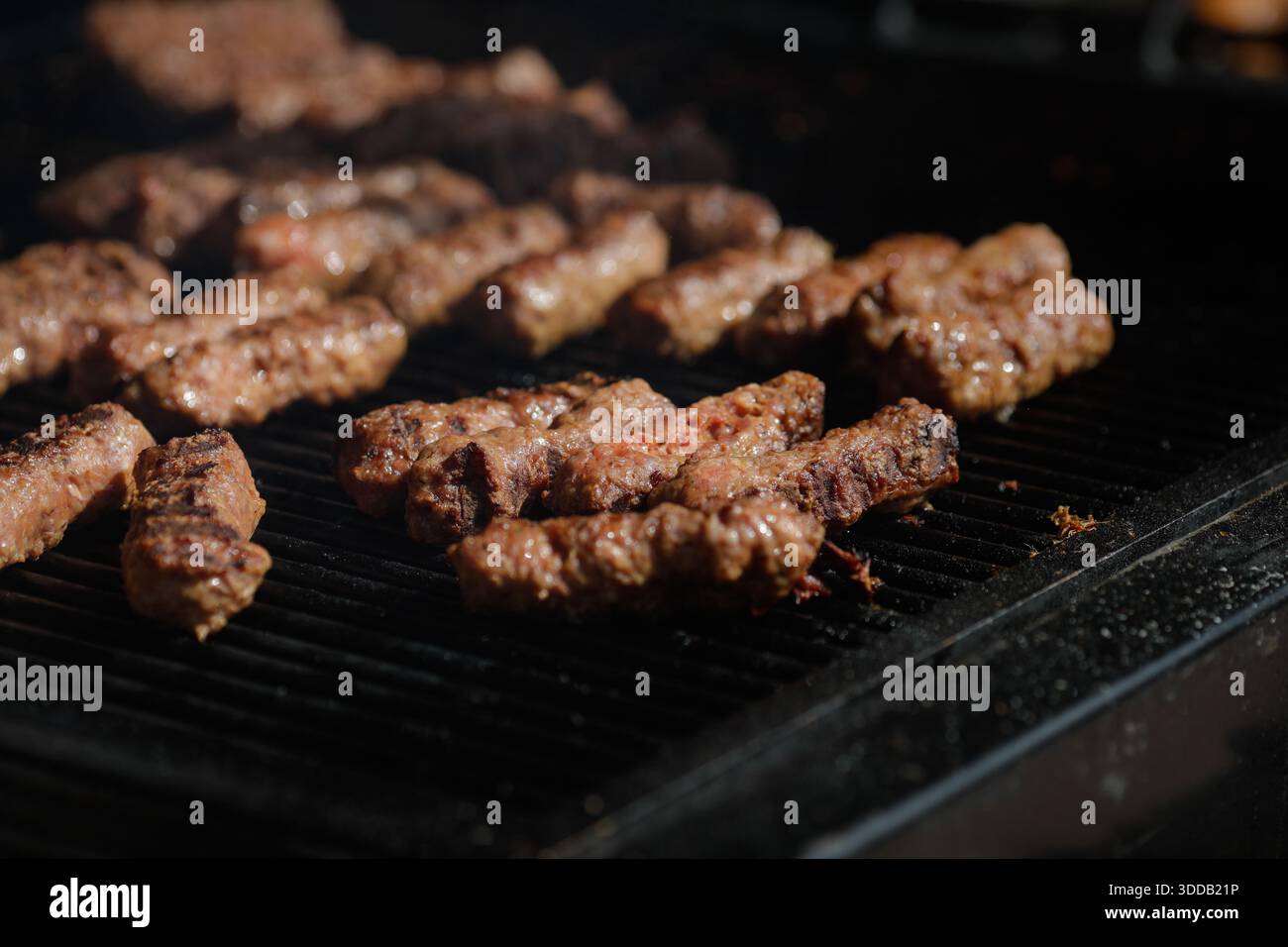 mici tradizionali rumeni (mititei o carne macinata laminata) su una griglia esterna in metallo carbone. Foto Stock