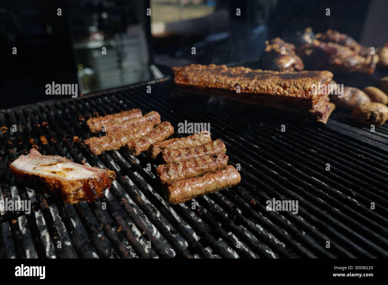 mici tradizionali rumeni (mititei o carne macinata laminata) su una griglia esterna in metallo carbone. Foto Stock