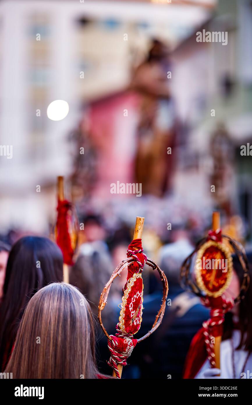Un colpo poco profondo in profondità di campo incentrato su un bastone di legno adornato da una corona di spine e velluto rosso, tenuto da un partecipante alla processione. Foto Stock