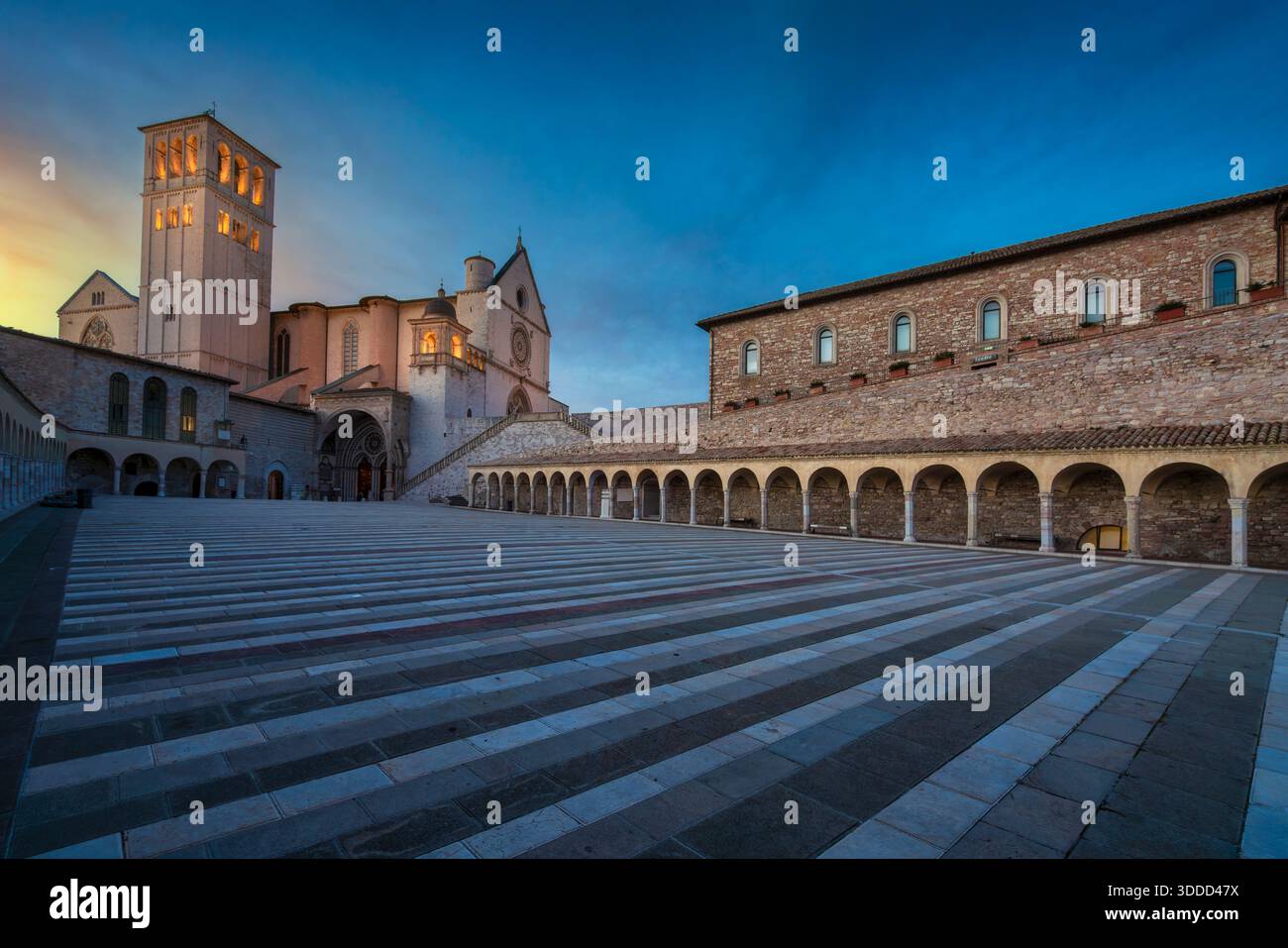 Vista di Piazza inferiore e della Basilica di San Francesco d'Assisi al tramonto. Sito storico patrimonio dell'umanità dell'UNESCO e meta di pellegrinaggio a um Foto Stock