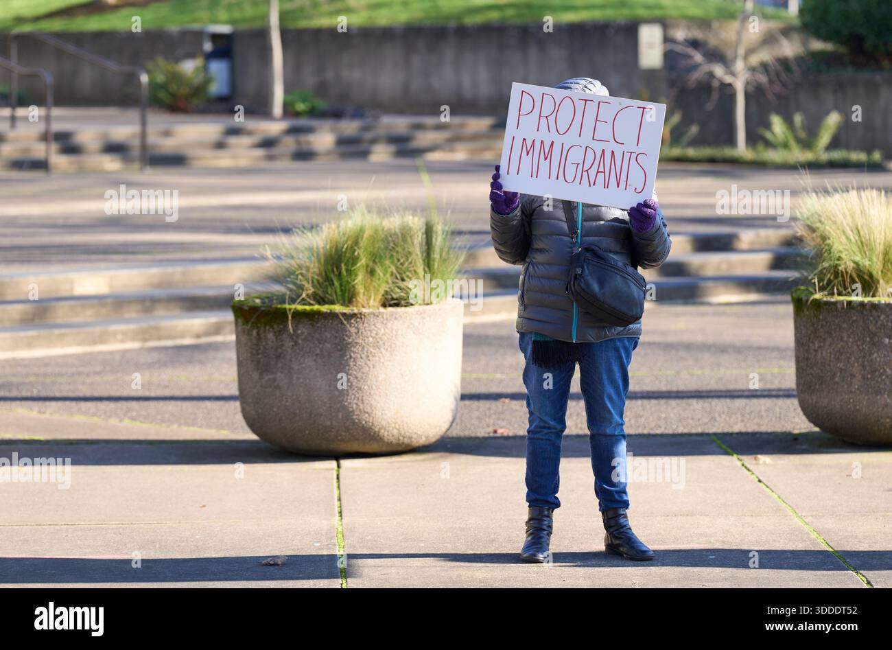 Una donna ha un segno contro le politiche di deportazione dell'amministrazione Trump durante una manifestazione del 30 dicembre 2025 a Eugene, Oregon. Foto Stock