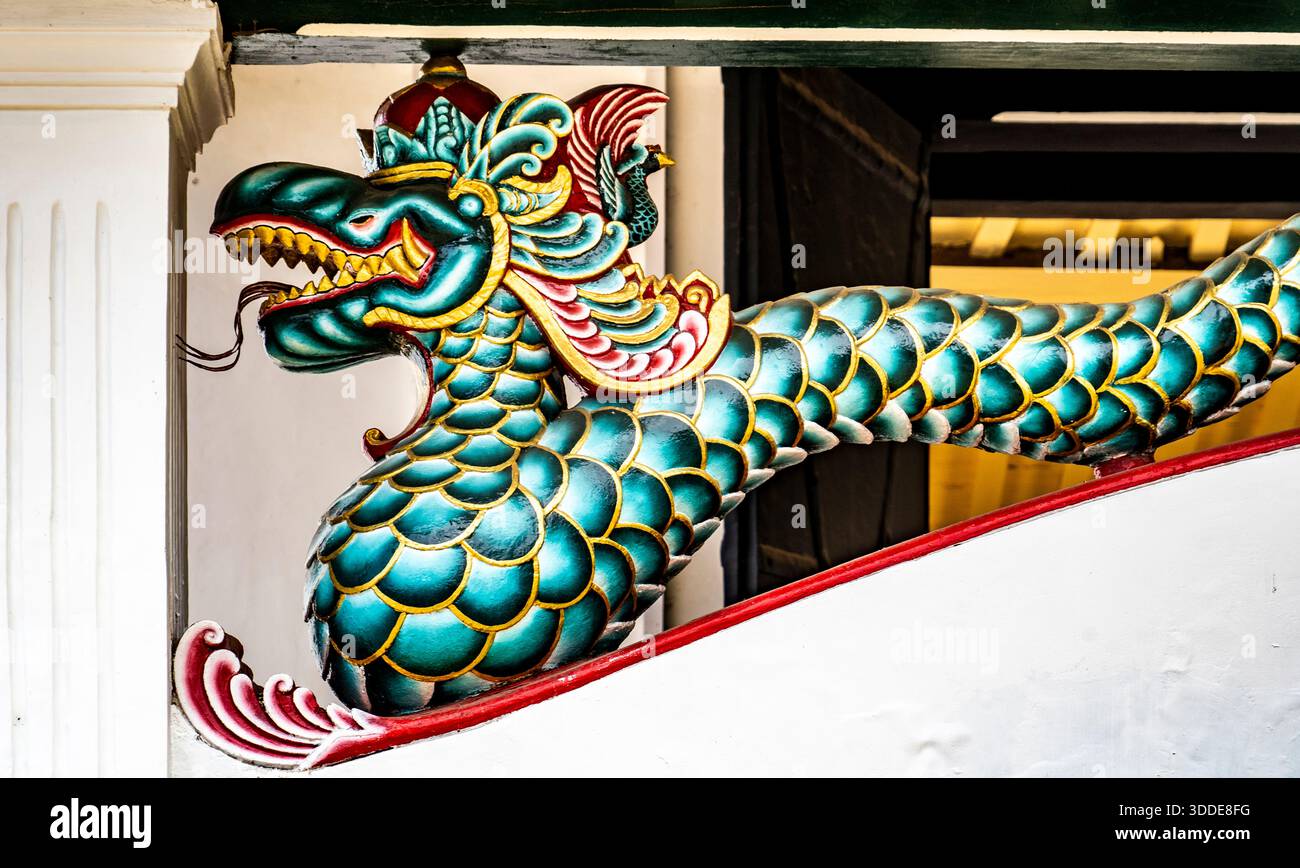 Colorata scultura di drago con scaglie e bocca aperta in un tempio. Foto Stock