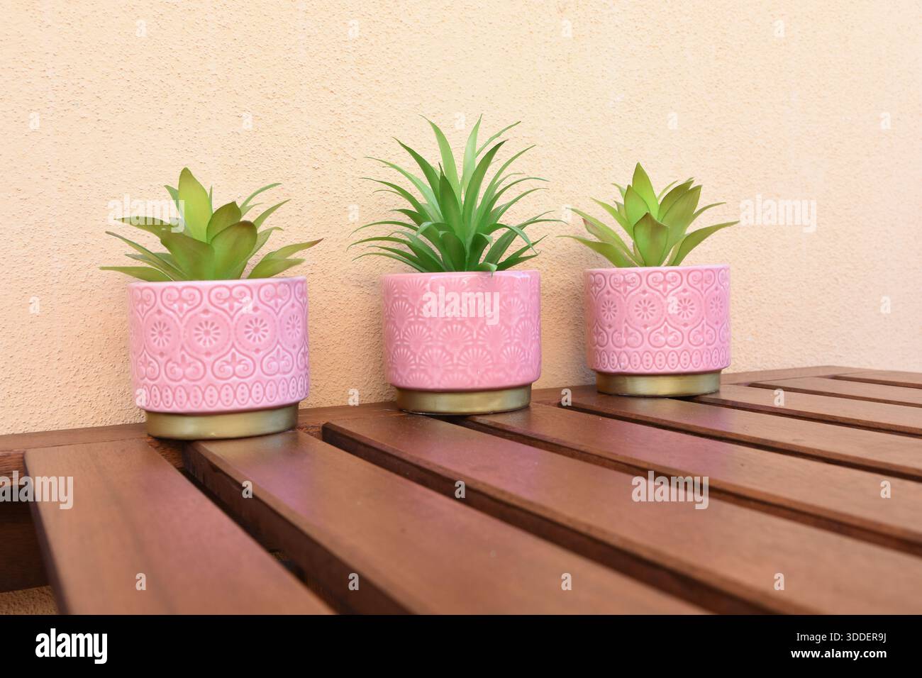 tre vasi rosa con fiori verdi artificiali sul tavolo del balcone Foto Stock
