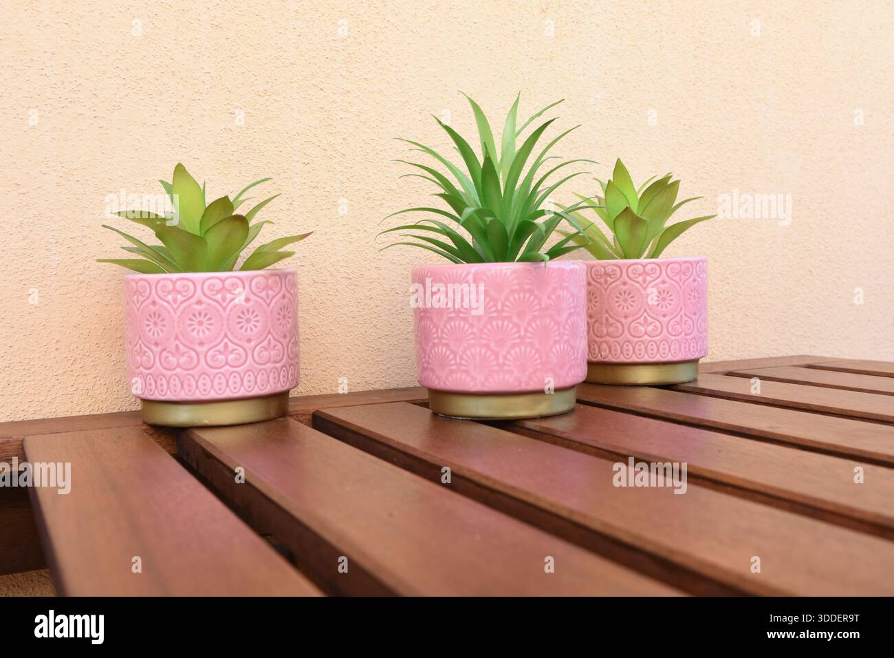 tre vasi rosa con fiori verdi artificiali sul tavolo del balcone Foto Stock