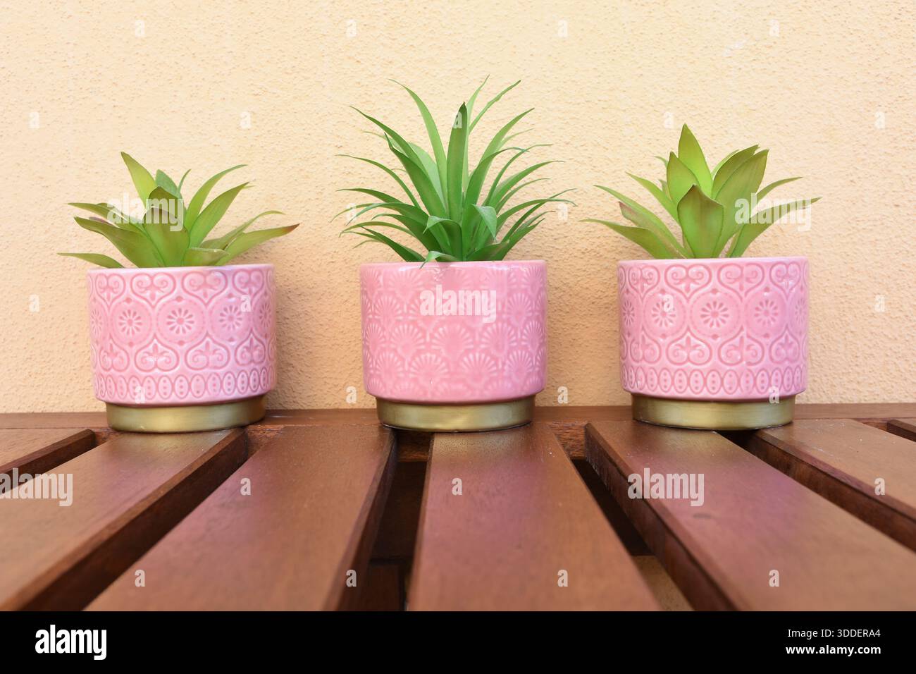 tre vasi rosa con fiori verdi artificiali sul tavolo del balcone Foto Stock