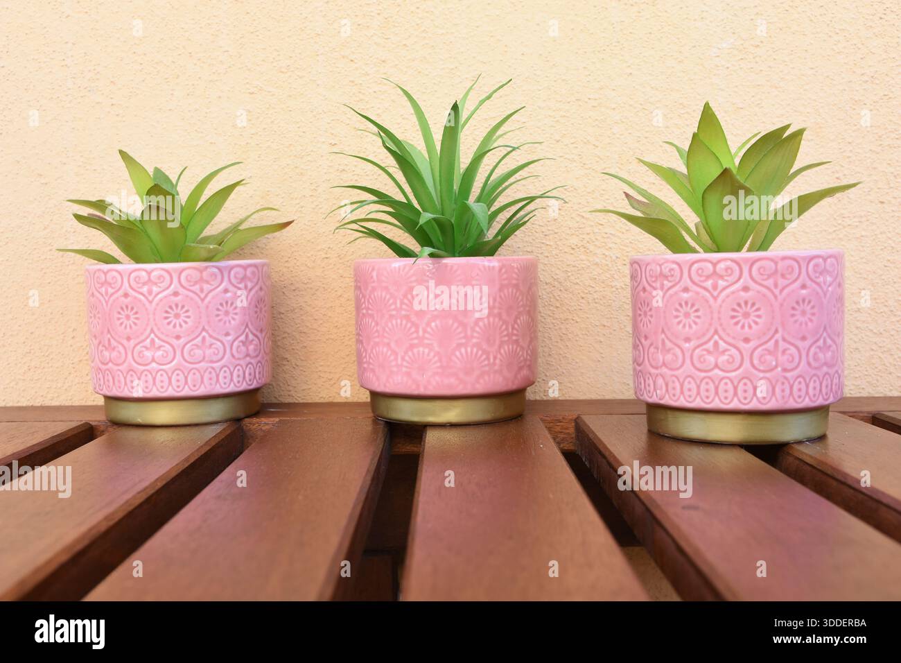 tre vasi rosa con fiori verdi artificiali sul tavolo del balcone Foto Stock