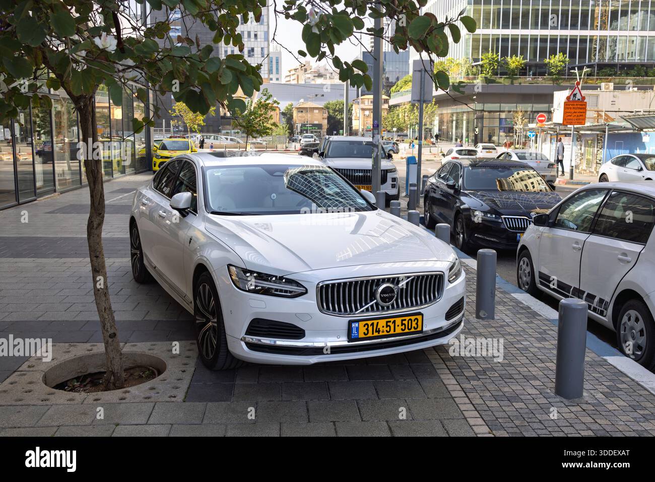 Berlina di lusso Volvo S90 bianca parcheggiata in una strada cittadina vicino a edifici di uffici moderni e alberi verdi, Ramat Gan, Israele, 24 dicembre 2025 Foto Stock