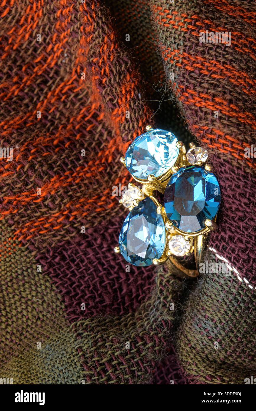 Primo piano di un anello blu in pietra preziosa appoggiato su tessuto testurizzato. Foto Stock