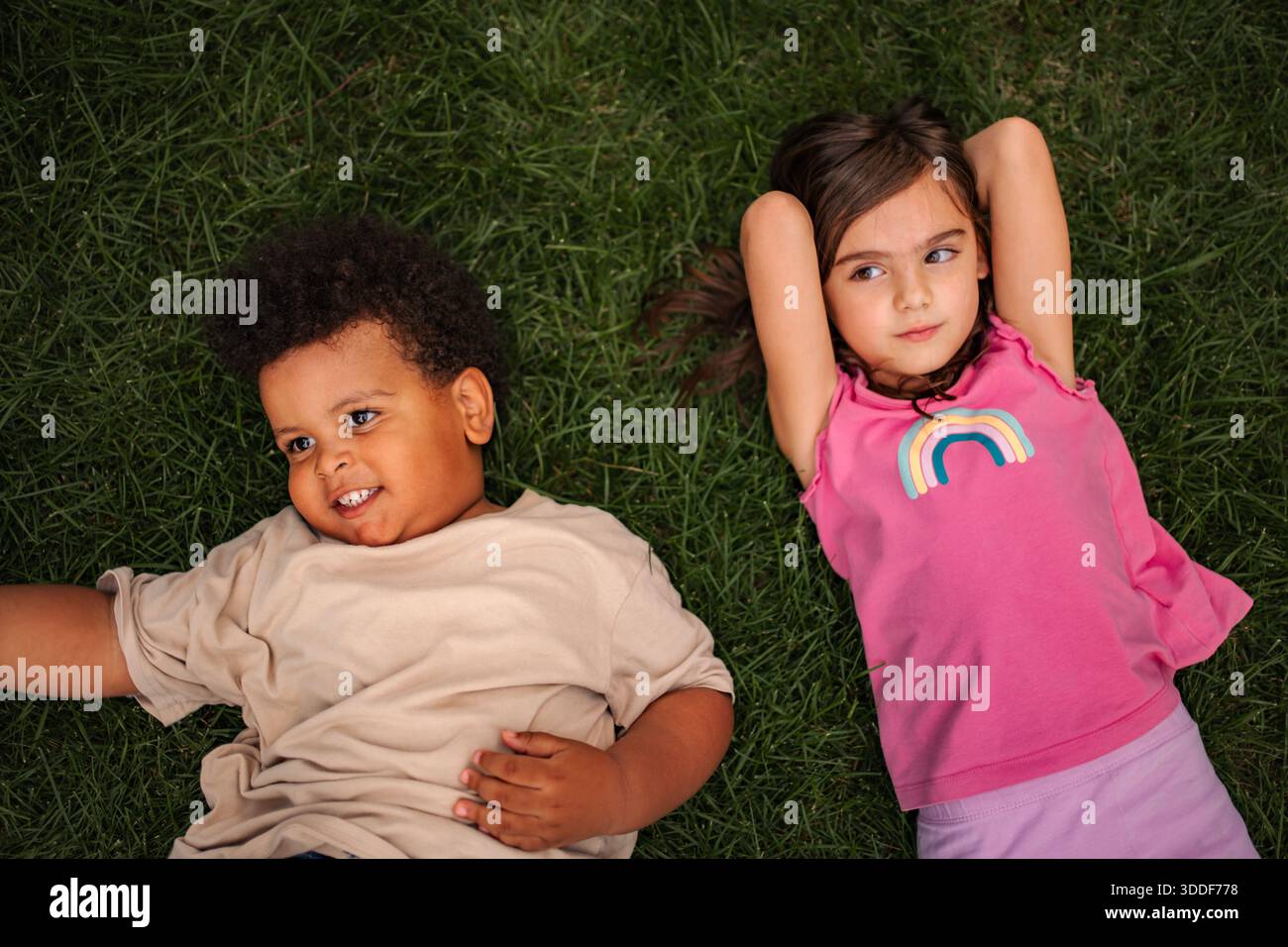 Bambini e amici diversi che giacciono sull'erba insieme Foto Stock