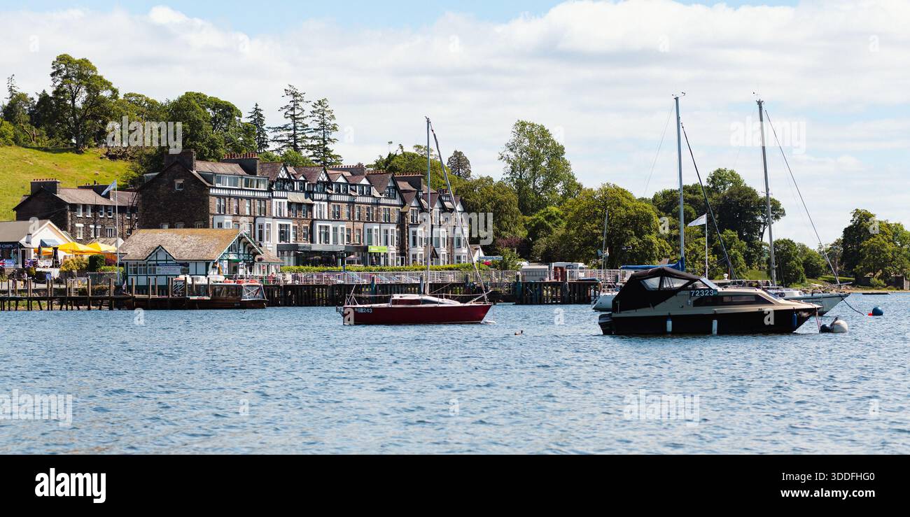 Barche ormeggiate vicino agli edifici sul lungomare sul lago Windermere Foto Stock