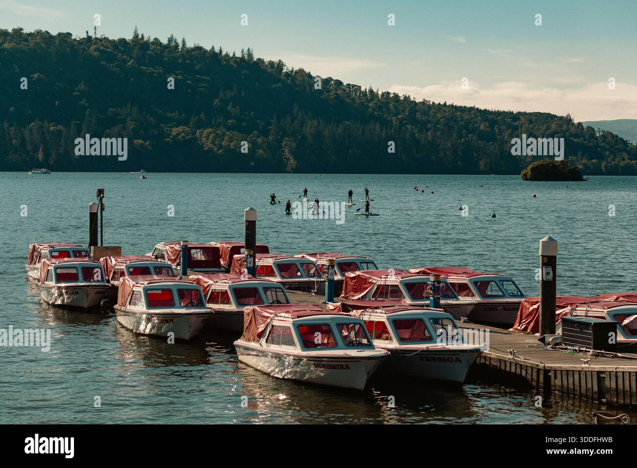 Pedalò ormeggiata sul lago Windermere con pedalatori in lontananza Foto Stock